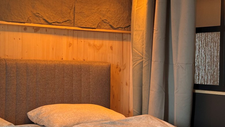 Familienzimmer- Kräuterhäusl Puchenstuben, © Kräuterhäusl Puchenstuben Gemütliches Schlafzimmer mit Doppelbett, Holzverkleidung und drei hängenden Lampen.