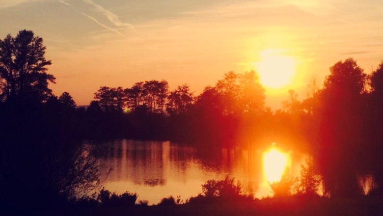 Sonnenuntergang am Ebersdorfer See, © zVg Gemeinde Ober-Grafendorf Sonnenuntergang über einem See mit Bäumen im Vordergrund.