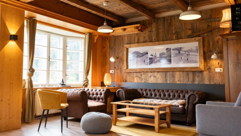 Kräuterhäusl Puchenstuben, © Kräuterhäusl Puchenstuben Gemütlicher Gemeinschaftsraum mit Holzwänden, Ledersofas und einem großen Fenster.