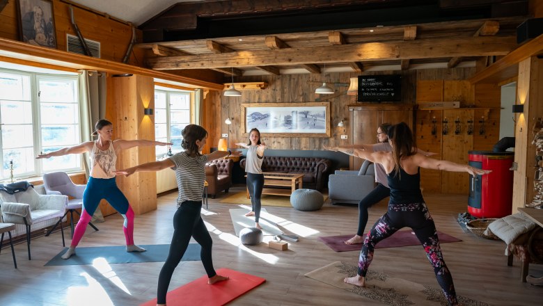 Yoga am Kräuterhäusl Puchenstuben, © Kräuterhäusl Puchenstuben Eine Gruppe Frauen praktiziert Yoga in einem gemütlichen Raum mit Holzwänden und großen Fenstern.