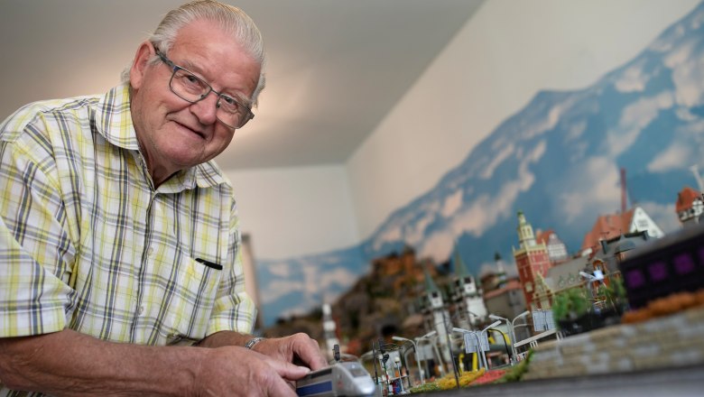 Opa Moser mit seiner Modelleisenbahn, © schwarz-koenig.at Opa Moser steht vor seiner Modelleisenbahnlandschaft und zeigt eine Lokomotive.