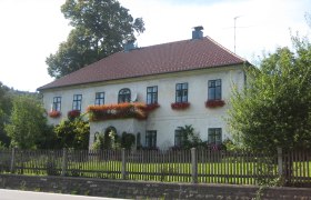 Ein zweistöckiges Haus mit roten Dachziegeln und Blumenkästen an den Fenstern.