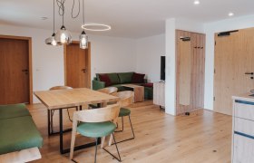 Modern eingerichtetes Wohn- Esszimmer mit Holzm&ouml;beln und gr&uuml;nen Akzenten.