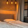 Gem&uuml;tliches Schlafzimmer mit Doppelbett, Holzverkleidung und drei h&auml;ngenden Lampen.