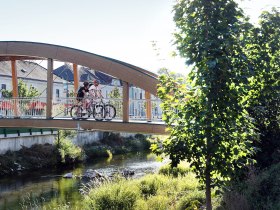 Radfahrende fahren &uuml;ber eine Br&uuml;cke.