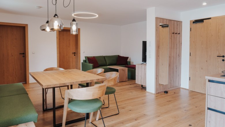 Modern eingerichtetes Wohn- Esszimmer mit Holzm&ouml;beln und gr&uuml;nen Akzenten.