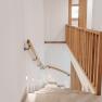 Moderne Treppe mit Holzgel&auml;nder und Wandbeleuchtung in einem hellen Innenraum.