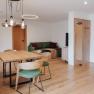 Modern eingerichtetes Wohn- Esszimmer mit Holzm&ouml;beln und gr&uuml;nen Akzenten.