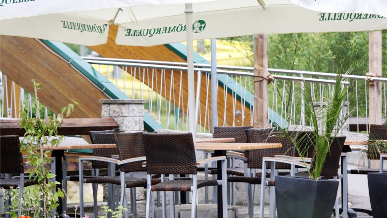 Gem&uuml;tliche Terrasse mit Tischen, St&uuml;hlen und Sonnenschirmen.