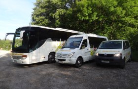Drei weiße Fahrzeuge mit Humpelstetter-Logo, geparkt auf einem Schotterplatz vor Bäumen.
