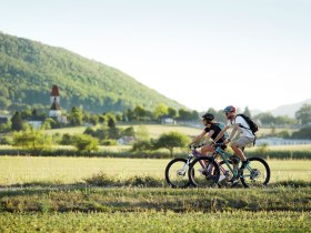 P&auml;rchen beim Radfahren, im Hintergrund ist eine Kirche zu sehen.