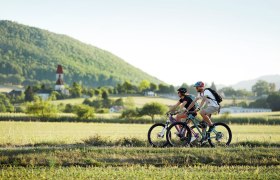 P&auml;rchen beim Radfahren, im Hintergrund ist eine Kirche zu sehen.