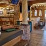 Aufenthaltsbereich mit rustikaler Einrichtung, Holzm&ouml;beln und einer Bar mit roten Hockern.